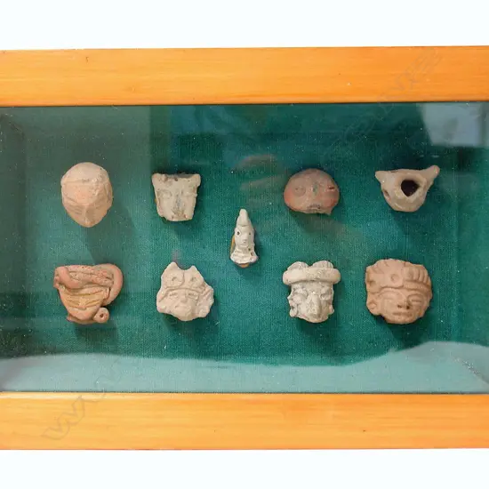 A collection of nine 'Pre-Columbian deity terra cotta heads' mounted in a glazed display box