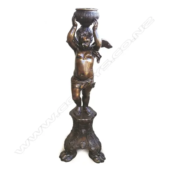 A tall bronze figure of a standing cupid holding bowl aloft