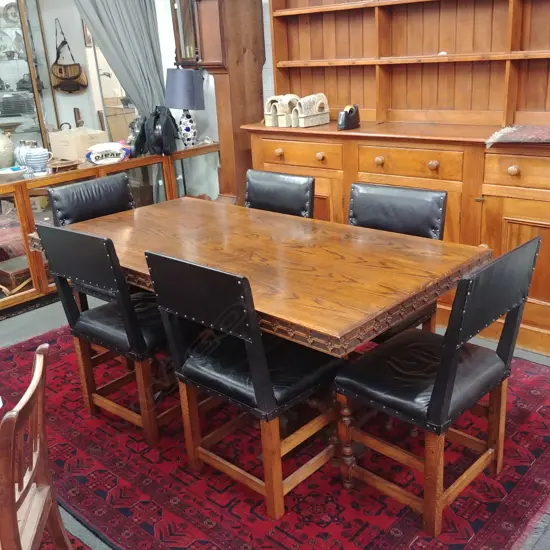 A c.1910 refectory oak dining table and six oak and leather upholstered chairs