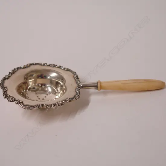 An early 20thC American silver and ivory handled tea strainer