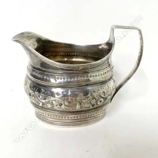 A Georgian flat-bottomed silver cream jug with embossed decoration