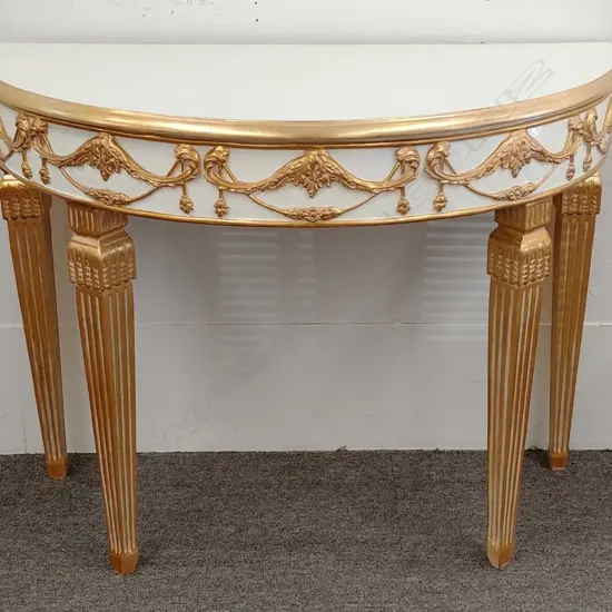 A modern cream paint finish and gold demilune side table