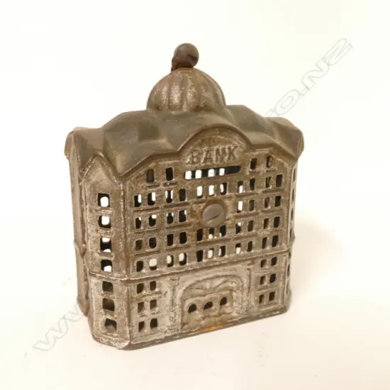 A vintage cast iron money box in the form of a bank building