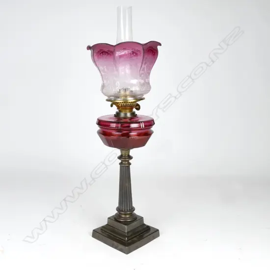A Victorian cast iron and cranberry kerosene lamp