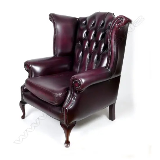 A large deep burgundy leather wing back armchair