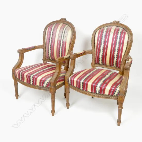 A pair of French Louis XVI style walnut open elbow chairs with cartouche backs