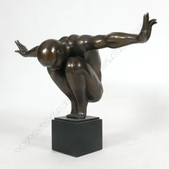 A bronze statue of a man in balanced toe stand pose