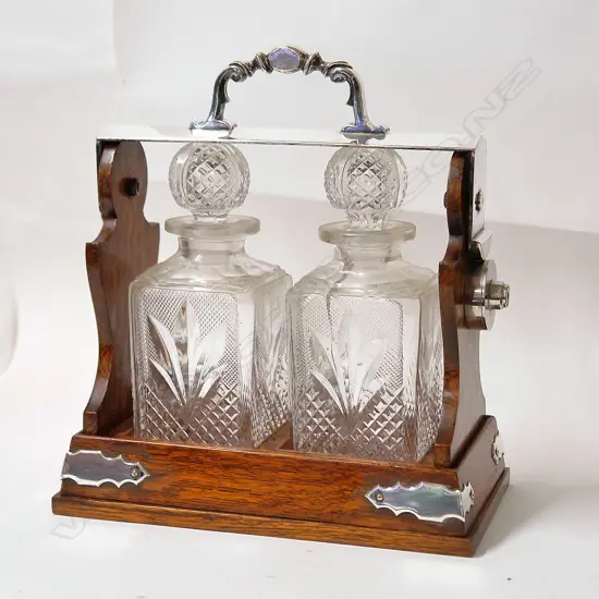 An Edwardian oak and silver plate two crystal bottle tantalus