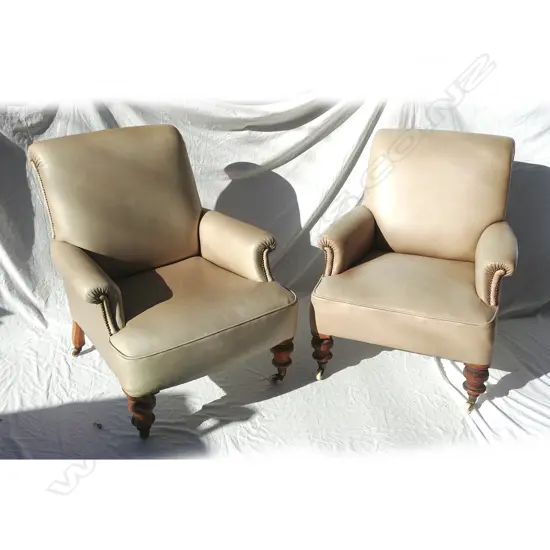 A pair of Victorian mushroom coloured leather armchairs of plain design with roll arms