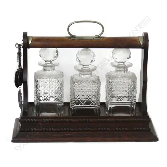 An Edwardian oak three bottle tantalus