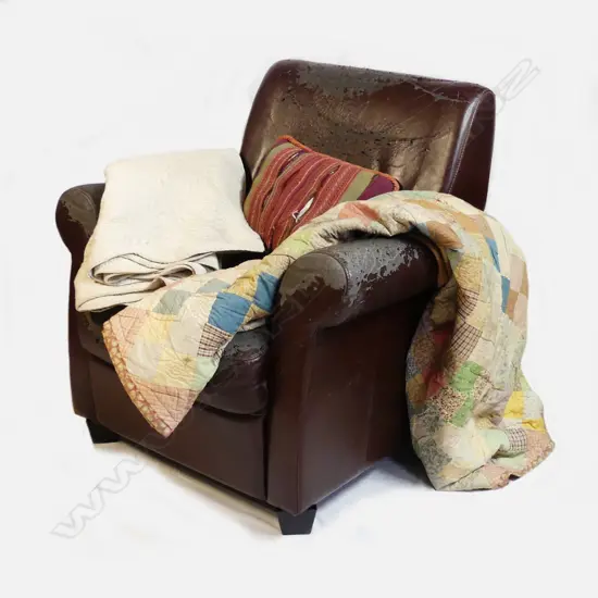 An old dark brown vinyl armchair with roll arms and short tapering square section legs - together with an old patchwork quilt