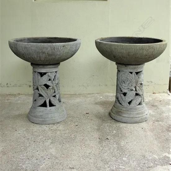 A pair of large modelled concrete urns on plinths
