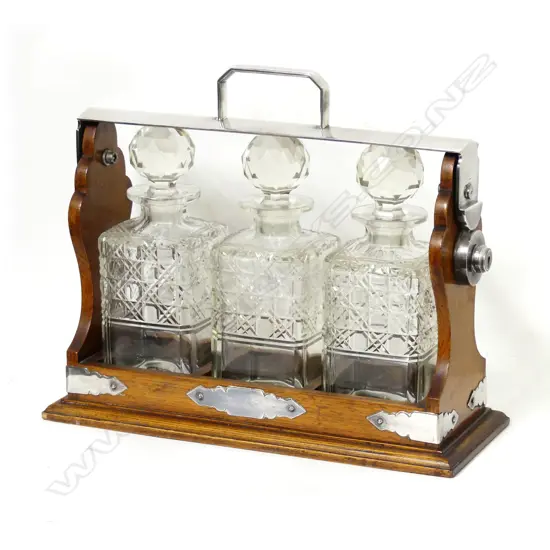 An Edwardian oak and silver plated framed three bottle tantalus