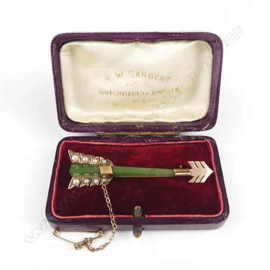 An Edwardian 9ct. rose gold greenstone and seed pearl arrow brooch