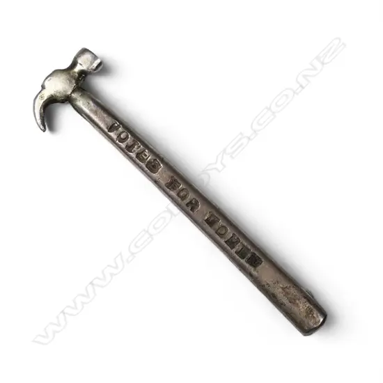 A silver brooch in the shape of a toffee or coke hammer with the inscription 'Votes for Women',