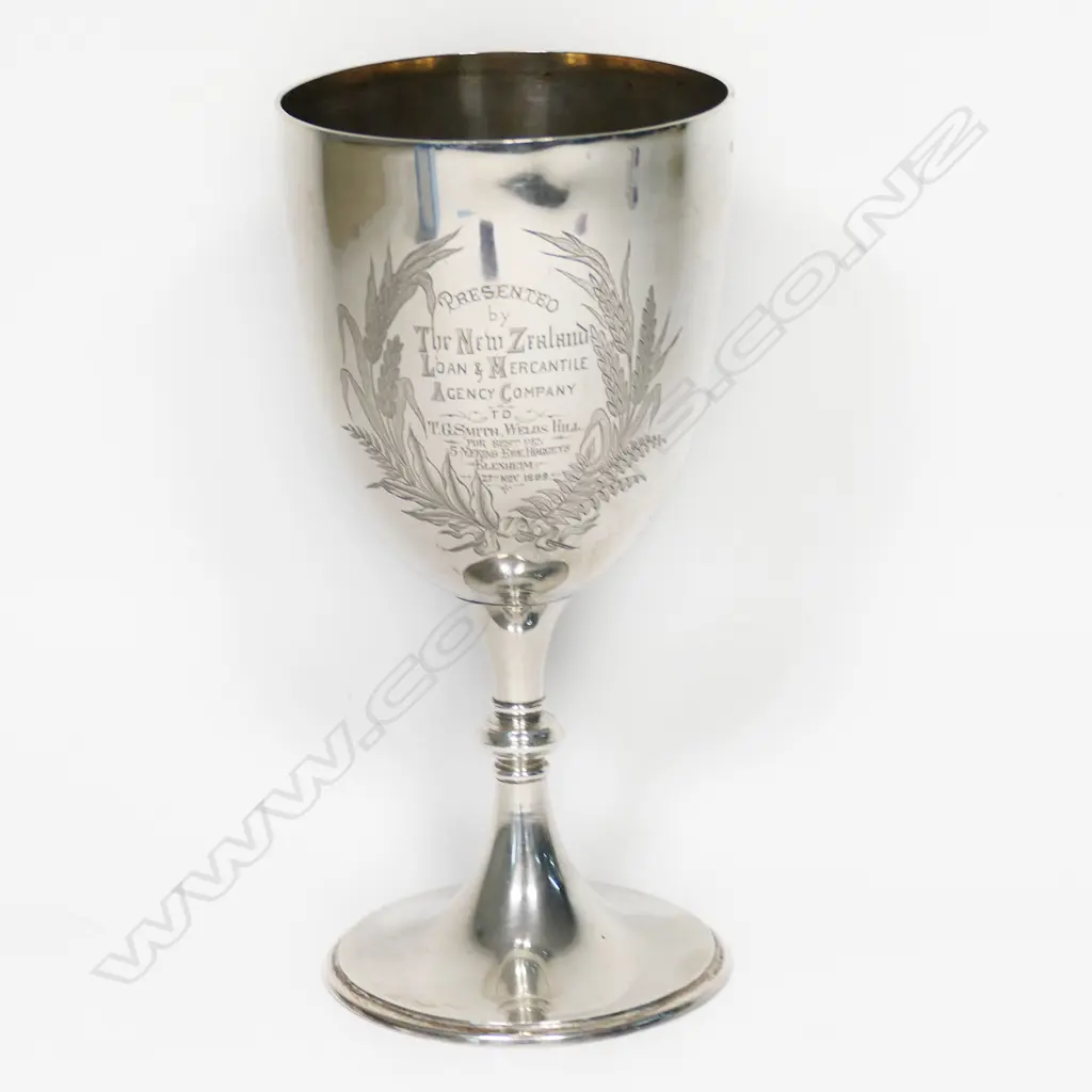 A New Zealand historical silver trophy cup - engraved 'Presented by The New Zealand Loan & Mercantile Agency Company To T.G. Smith, Wells Hill. For Best Pen 5 Merino Ewe Hoggets. Blenheim. 27th Nov. 1889'. Engraved to the front with a colonial mountain and pastoral landscape with sheep and a cow. H.235mm. 308gms Image 1++
