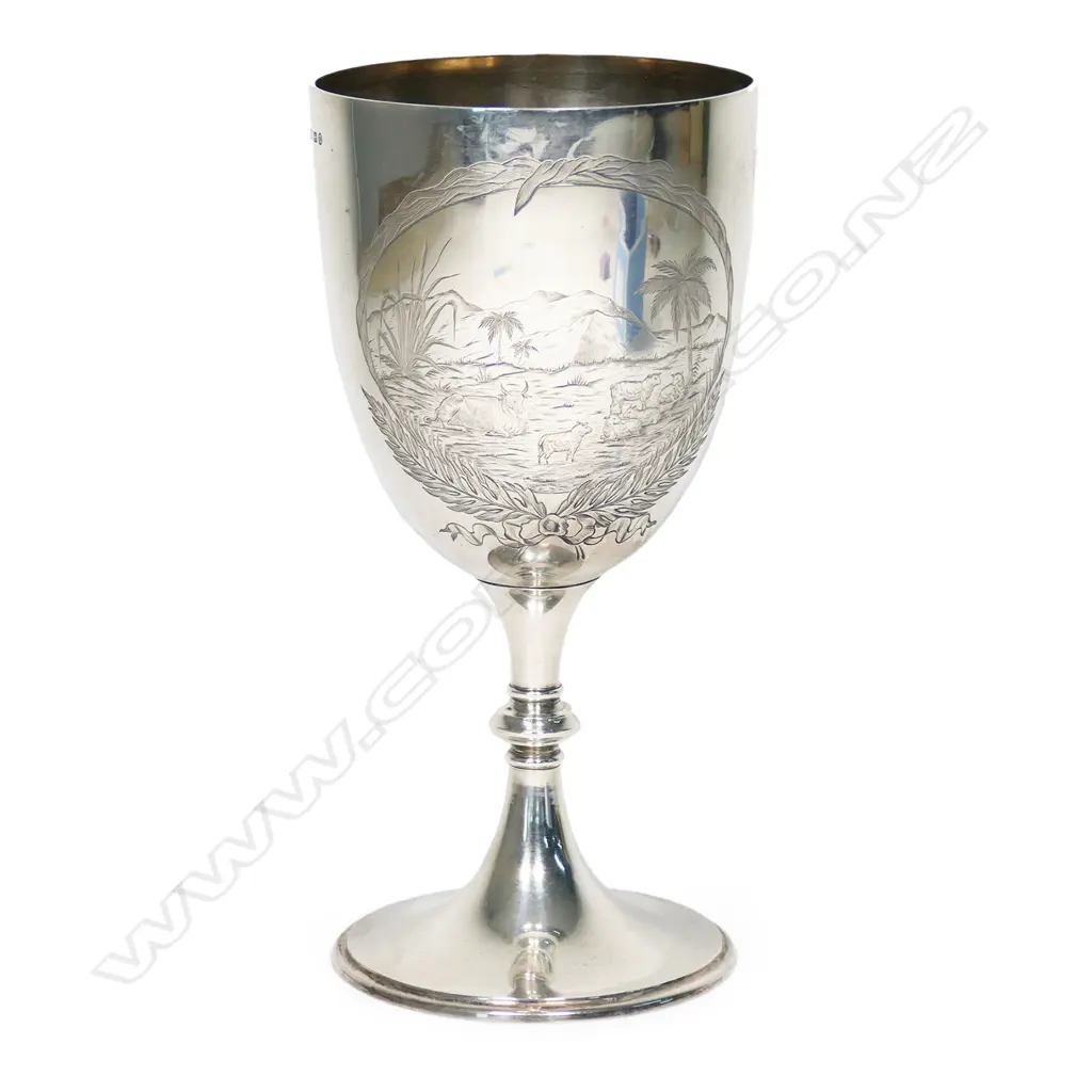 A New Zealand historical silver trophy cup - engraved 'Presented by The New Zealand Loan & Mercantile Agency Company To T.G. Smith, Wells Hill. For Best Pen 5 Merino Ewe Hoggets. Blenheim. 27th Nov. 1889'. Engraved to the front with a colonial mountain and pastoral landscape with sheep and a cow. H.235mm. 308gms Image 1++