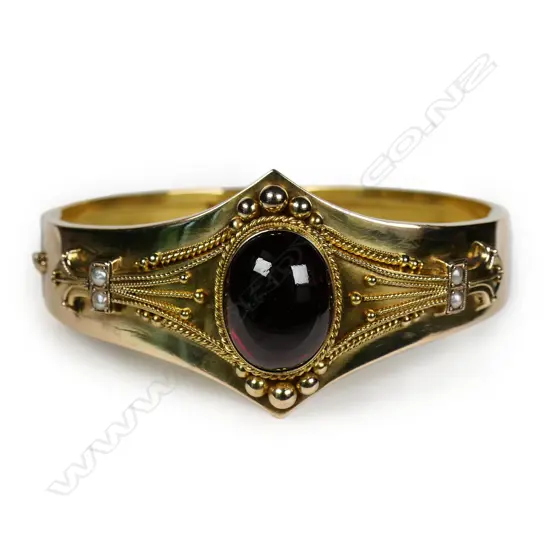 A Victorian Etruscan revival 15ct gold cabochon garnet hinged bangle,