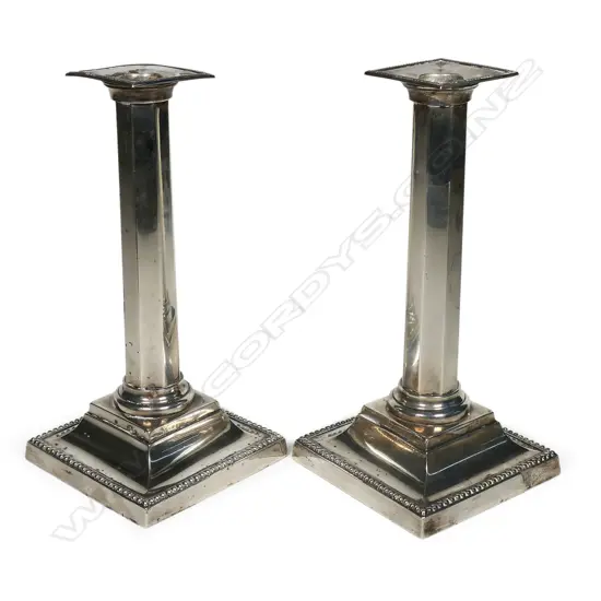 A pair of elegant silver column candlesticks, by Martin Hall & Co., Sheffield 1898 - of slightly tapering octagonal section, raised on bead edged ogee plinth bases and with conforming nozzles. H.230mm. Weighted bases