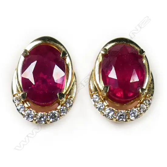 A pair of 18ct yellow gold ruby and diamond earrings - the oval facet cut rubies of good bright tone and clarity, with a curve of seven diamonds to one end and a plain gold curve the other. Fittings for pierced ears. 2.97gms.