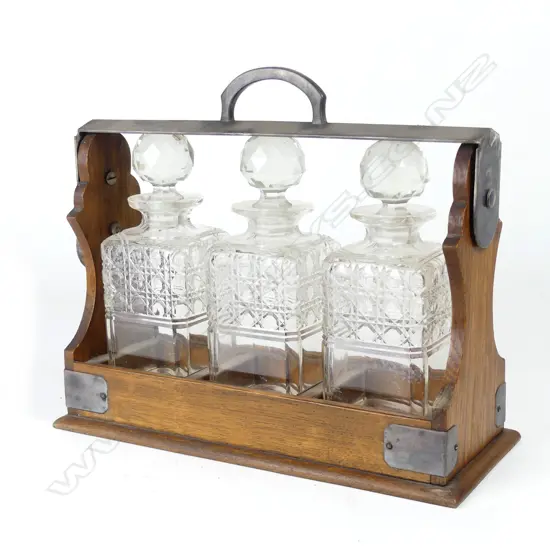 An Edwardian oak and silver plate framed three-bottle tantalus