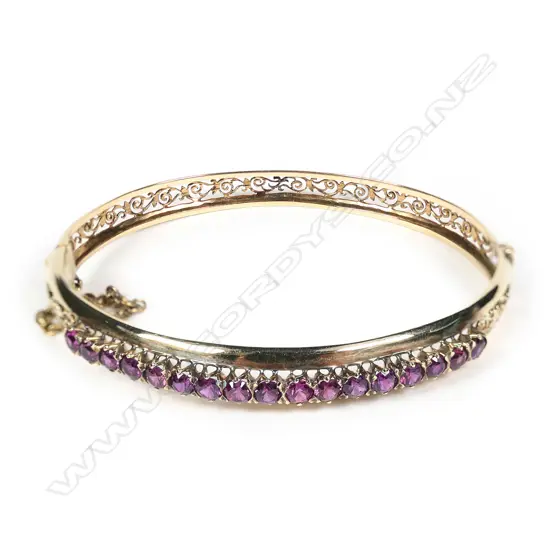 An early 20thC 18ct yellow gold and 17 Garnets set hinged bangle