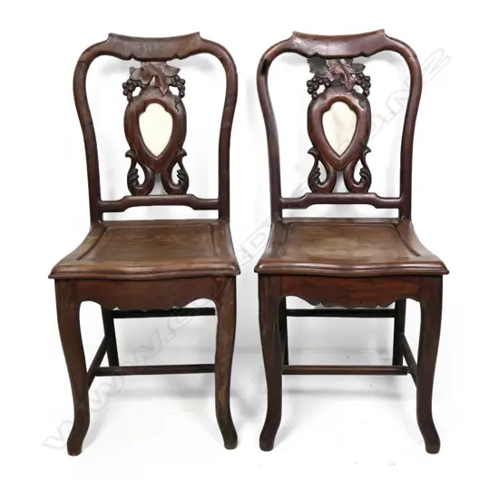 A pair of vintage Chinese rosewood side chairs, the shield back panels set with marble inserts and framed by grape bunch and leaf carving with scroll supports, panelled seats, stretched legs.