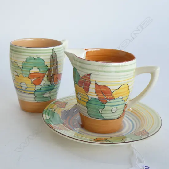 A Clarice Cliff Bizarre coffee cup and saucer and matching milk jug, floral pattern with concentric banding.