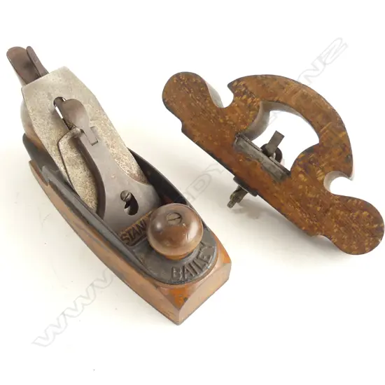 A Stanley Plane and a wooden 'D' router, the plane with a wooden bottom, the beech router of scrolling 'D' form with metal fittings.