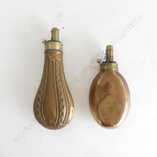 Two copper gunpowder flasks; one bag shaped marked ‘Dixon & Sons’ on the graduated nozzle the body with chain link moulding; the other plain and unmarked.