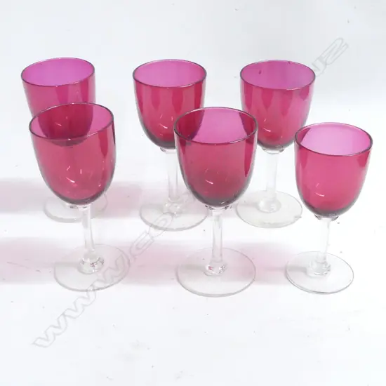Six Victorian cranberry glass goblets with clear stems and circular feet. Approx. H.130mm. One slightly smaller.