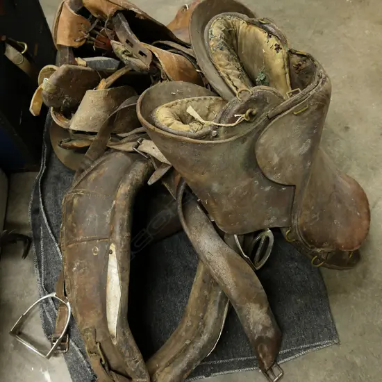 Three old leather military saddles and a horse collar