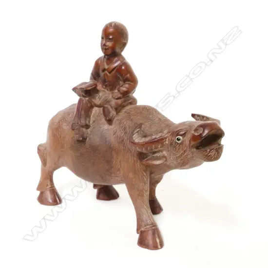 A carved rosewood figure depicting a boy riding a bullock