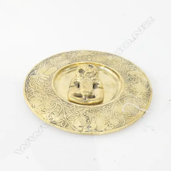 A BRASS PLATE WITH APPLIED HEI TIKI AND MAORI MOTIF BORDER D 240 MM 