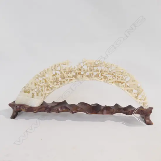 A CHINESE CARVED HIPPOPOTAMUS TUSK ON A ROSEWOOD STAND. W.320mm.