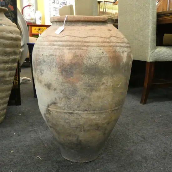 An old European terracotta tall olive oil storage jar