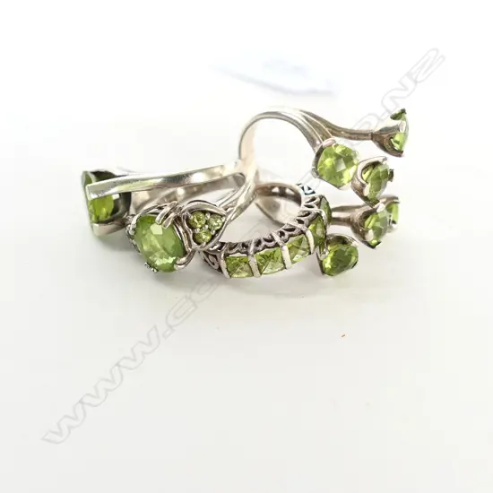 FOUR SILVER AND PERIDOT RINGS