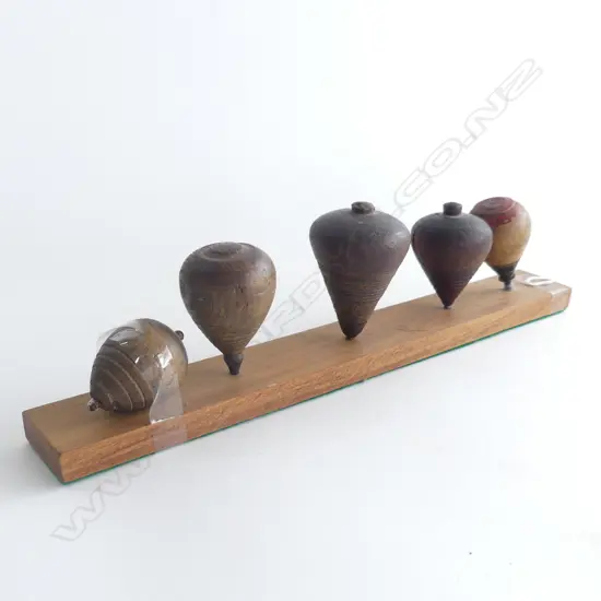 (90) A SET OF 5 SPINNING TOPS ON PURPOSE MADE BOARD 320MM LONG