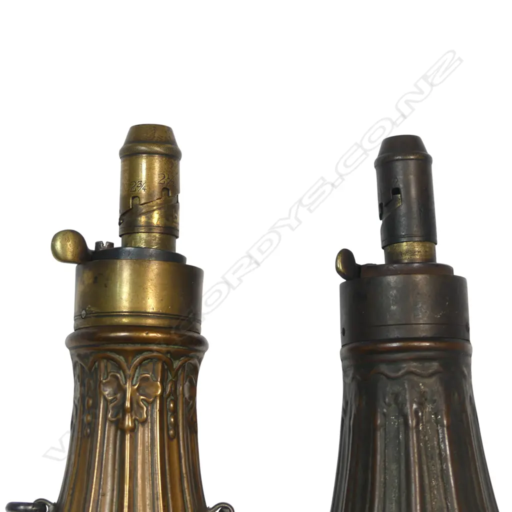 Two copper and brass bag-shaped shot flasks, one by G & J W Hawksley  with graduated dispenser nozzle (2¼, 2½, 2¾ and 3 drams), decorated with a fluted and moulded acanthus and hop design. The other unnamed. Image 1++