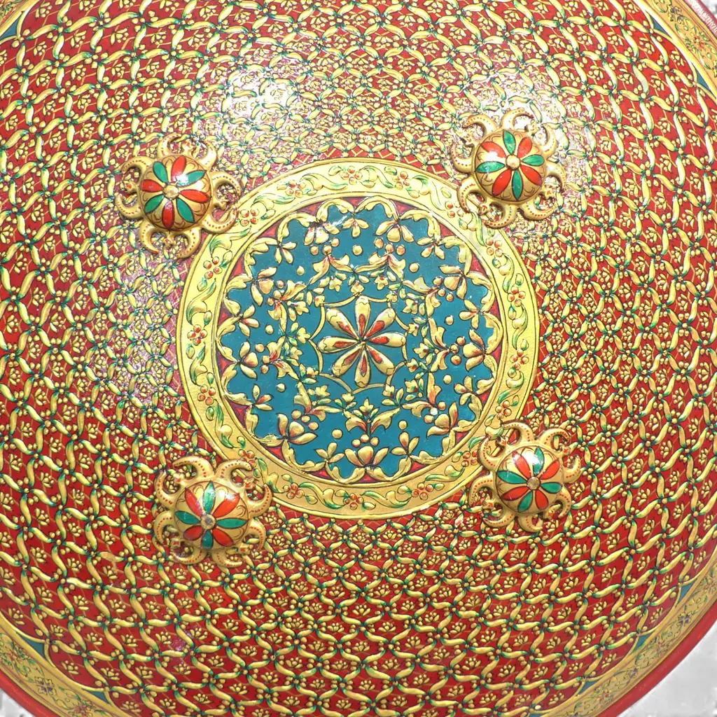 Two Tulwar Swords and matching Dahl Shield from the Punjab Region, India. A matching pair of 28" deeply-curved wootz blades with a gold cartouche to each; double-edged tips and serrated notch-backed to 3/4 of their lengths. The hilts are profusely gold damascened (one with a pommel spike, the other a dome). Matched leather scabbards with raised gilding on a red ground. Along with a matching Dahl shield, dia.20". Believed to have been made as a presentation set. Image 1++