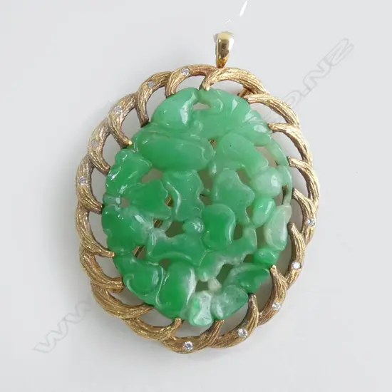 An impressive bright green carved jadeite pendant, in 18ct. heavy gold frame,