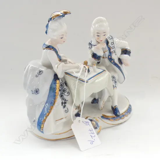 JAPANESE PORCELAIN FIGURALGROUP IN GERMAN MANNER COUPLE PLAYING CHESS 140MM HIGH 140MM WIDE