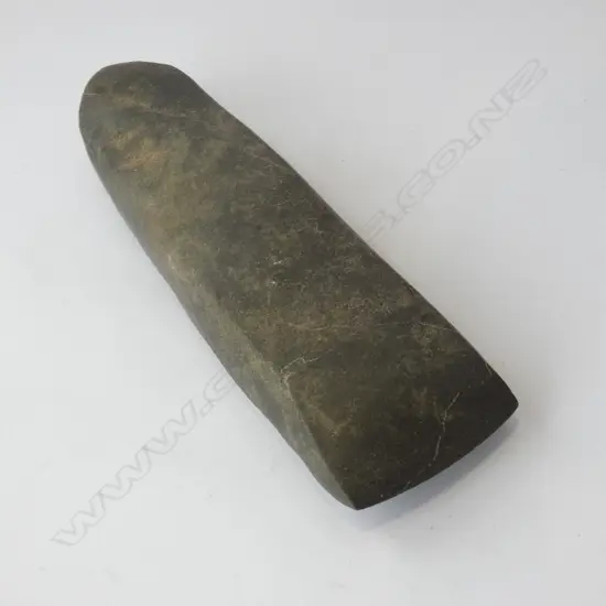 Complete adze. Trapezoidal cross section; narrower back than front. Cortex remnants front / proper left side and back. Ground all over. Rounded poll. Impact scar on front proper right near poll. Shallow bevel. Sharp