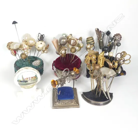 Three hat pin stands, three hat pin cushions and collection of hat pins.