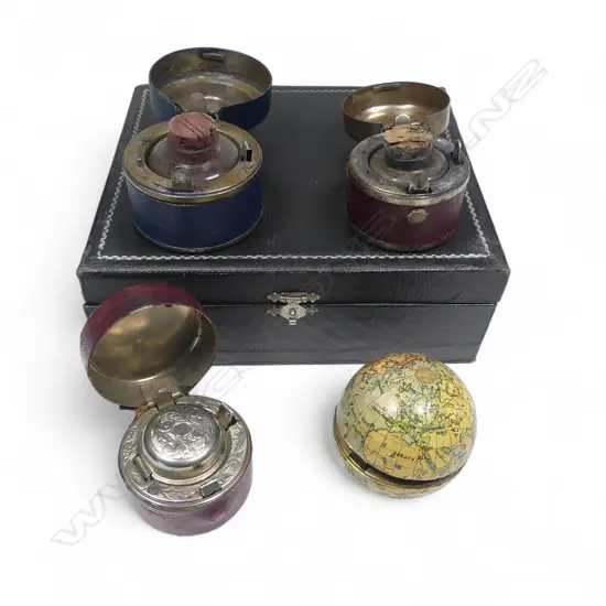 Four travelling inkwells, including one formed as a world globe, of gilt metal overlaid with lithographed paper gores printed in German language, 1900. Dia.50mm.