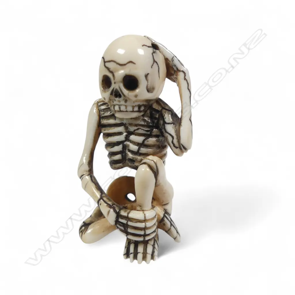 Japanese ivory netsuke of a skeleton, humorously rendered sitting cross-legged with one hand to his skull the other clasping his ankle,  signed to the foot 'Matsuyama'. H.55mm Image 1++