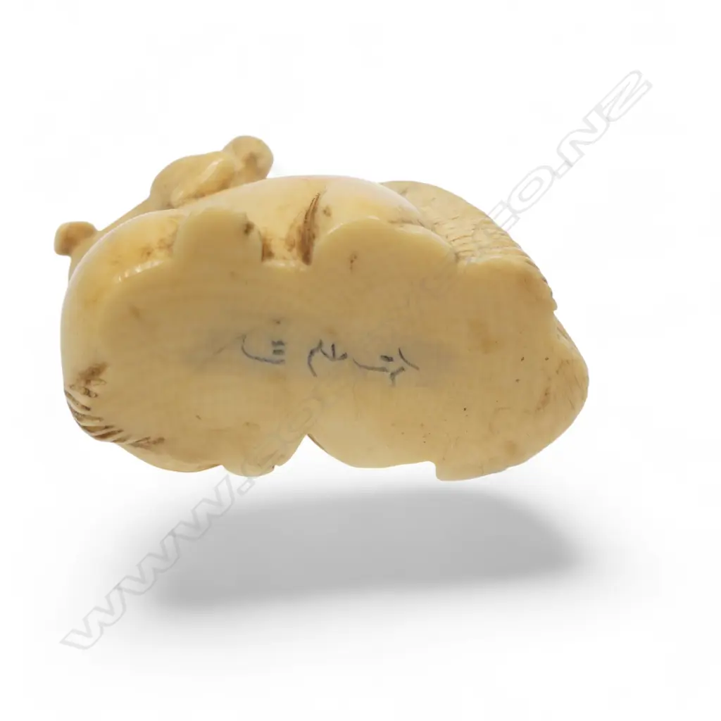 A Japanese ivory netsuke of a puppy standing on the haunches of a seated horse, three character signature under the base. L.40mm Image 1++