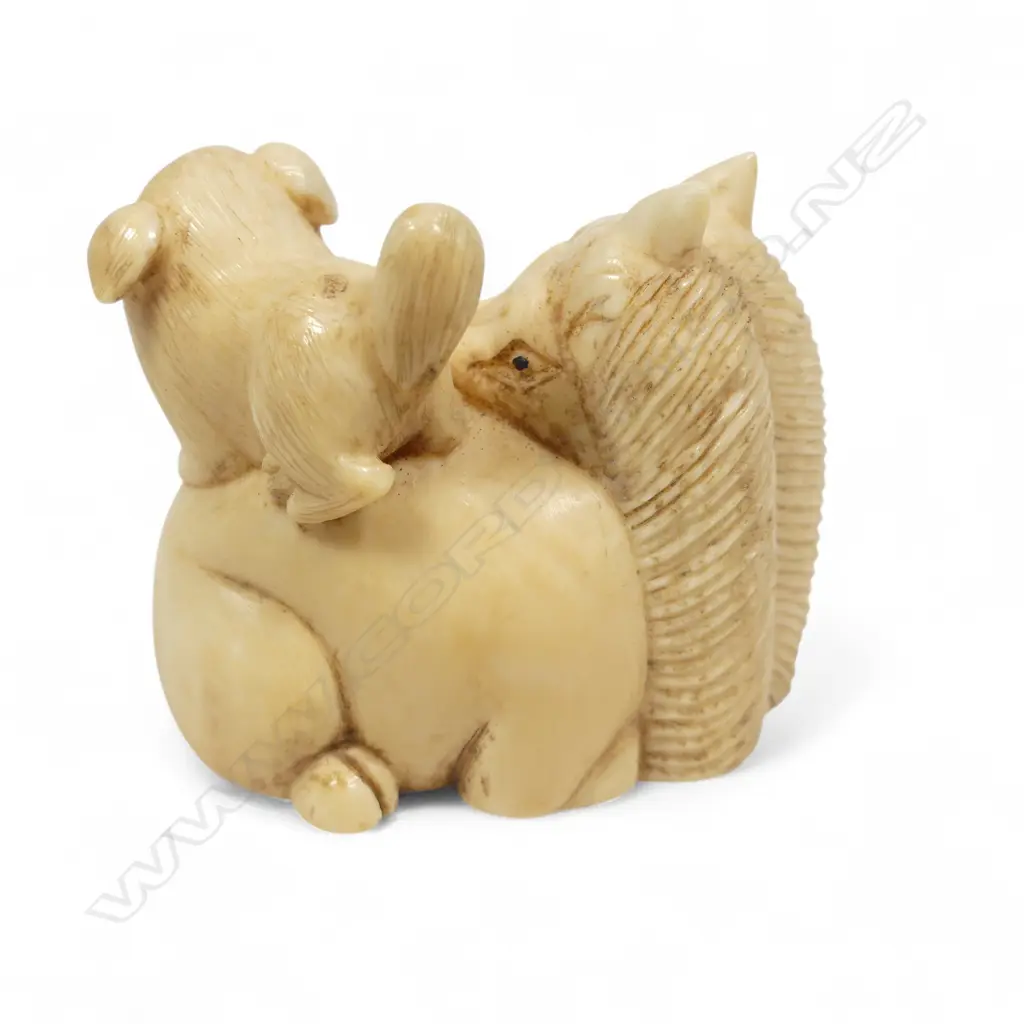 A Japanese ivory netsuke of a puppy standing on the haunches of a seated horse, three character signature under the base. L.40mm Image 1++