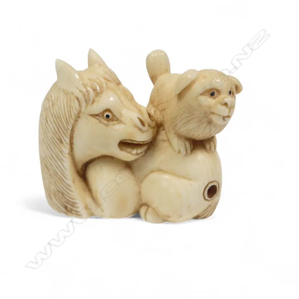 A Japanese ivory netsuke of a puppy standing on the haunches of a seated horse, three character signature under the base. L.40mm Image 1++