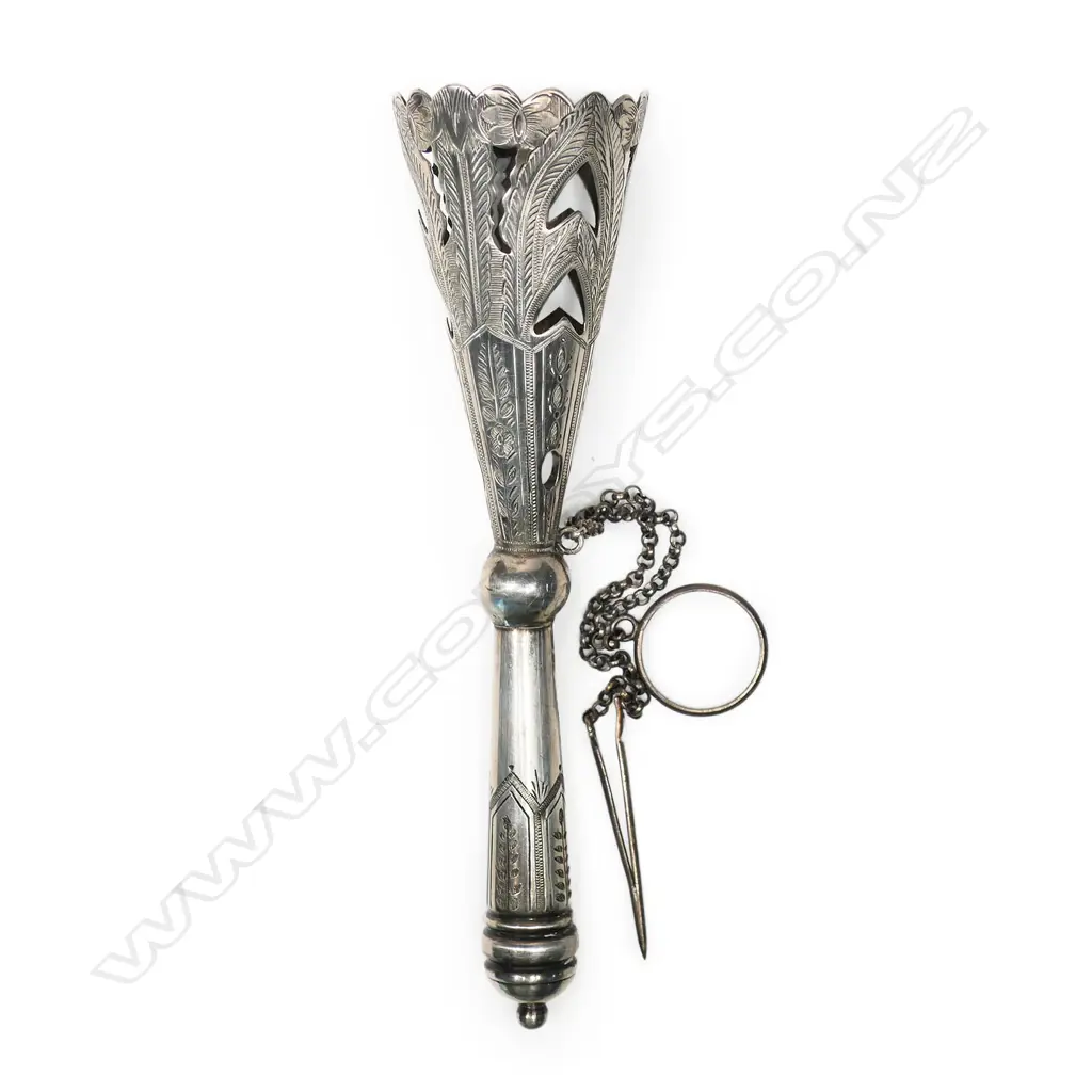A late Victorian silver plated tussie-mussie, the cone pierced and engraved with stiff leaves, on a tapering handle with pennant frieze engraving. With finger-ring and pin on chains. H.135mm Image 1++